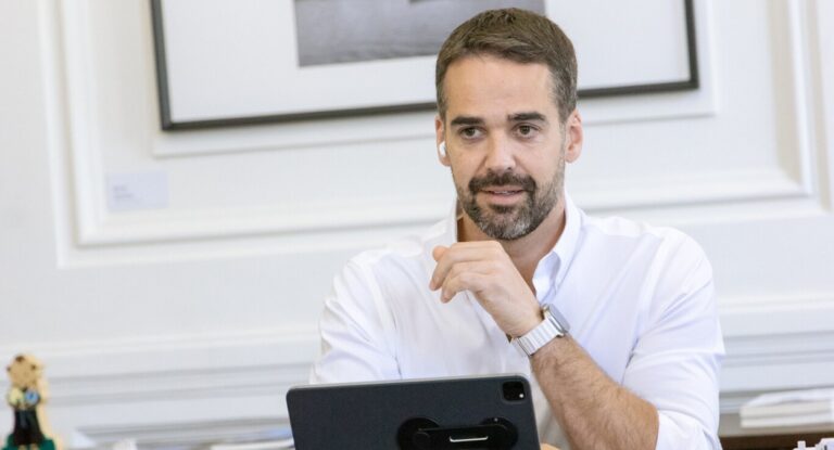 Eduardo Leite sentado em uma mesa olhando para a cãmera