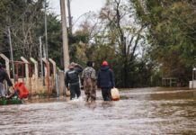 Imagem mostra moradores de Canoas em área alagada com água até as canelas após alerta de inundação