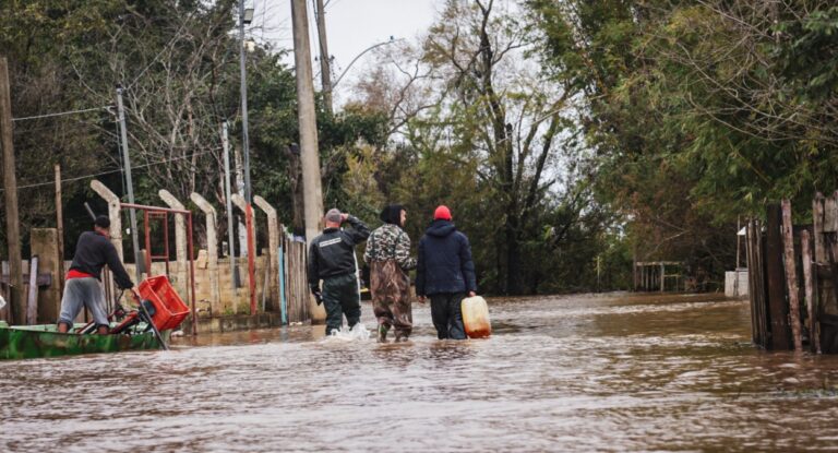 Imagem mostra moradores de Canoas em área alagada com água até as canelas após alerta de inundação
