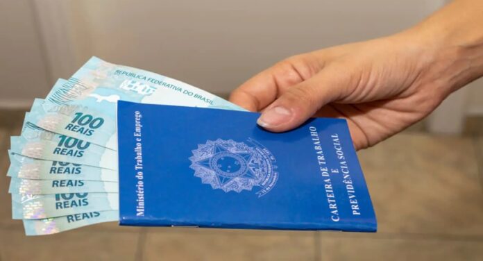 Mão de trabalhador segurando carteira de trabalho e dinheiro de crédito consignado CLT