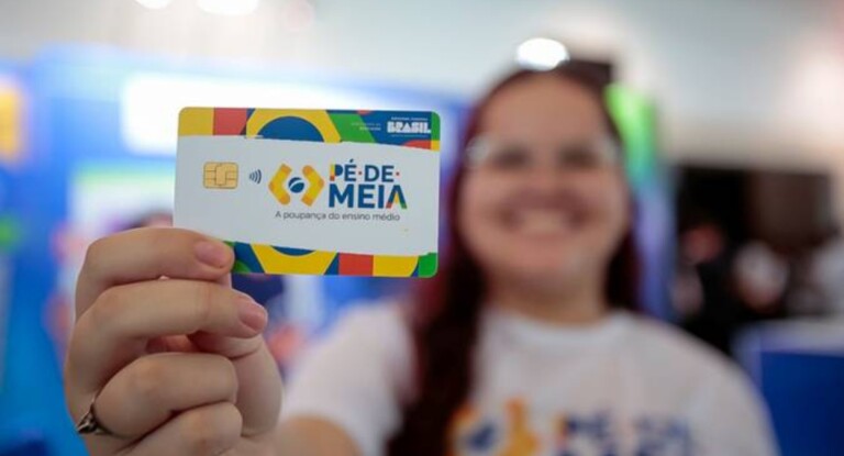 Imagem de uma menina segurando um cartão do programa federal pé-de-meia