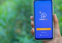 Mão segurando celular com aplicativo do Caixa Tem