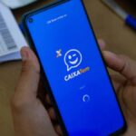 Foto mostra uma pessoa segurando um celular com o aplicativo do Caixa Tem aberto