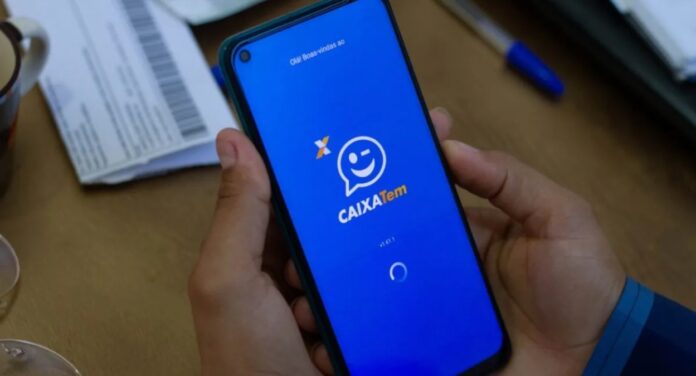 Foto mostra uma pessoa segurando um celular com o aplicativo do Caixa Tem aberto