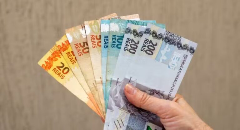 Foto mostra mão segurando dinheiro de saque emergencial do Caixa Tem