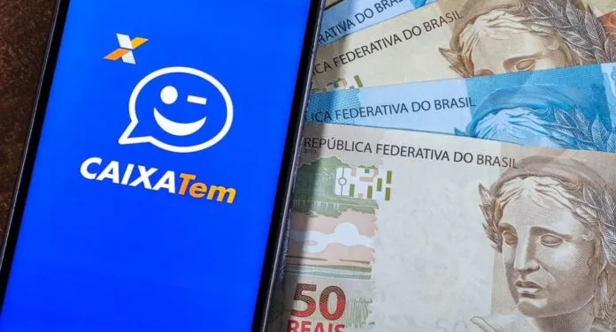 Celular com aplicativo do Caixa Tem e cédulas de dinheiro ao fundo
