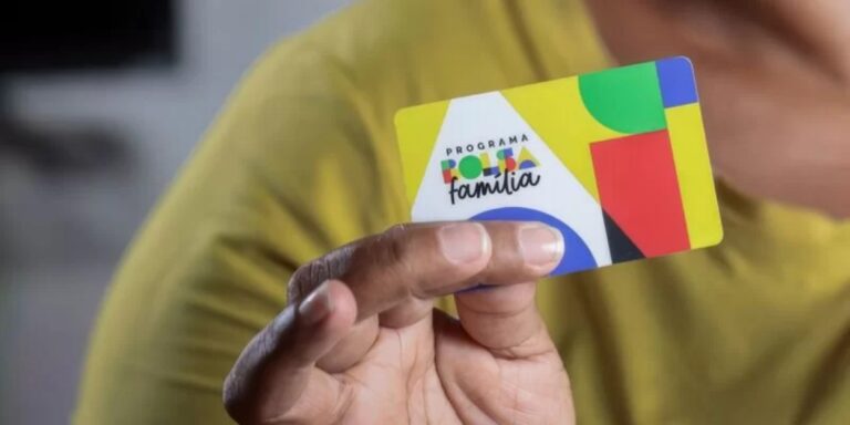 Na imagem uma mão segurando um cartão do Bolsa Família