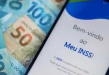 App do Meu INSS aberto em um celular com cédulas de real ao fundo