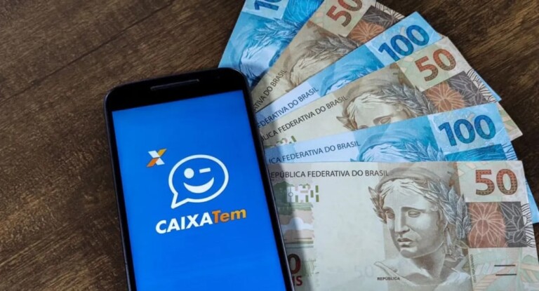 Celular com o app do Caixa Tem aberto e cédulas de dinheiro ao fundo