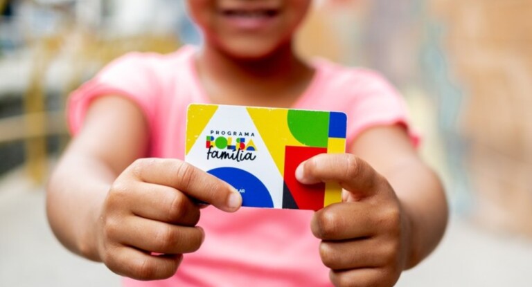 Menino segurando cartão do Bolsa Família