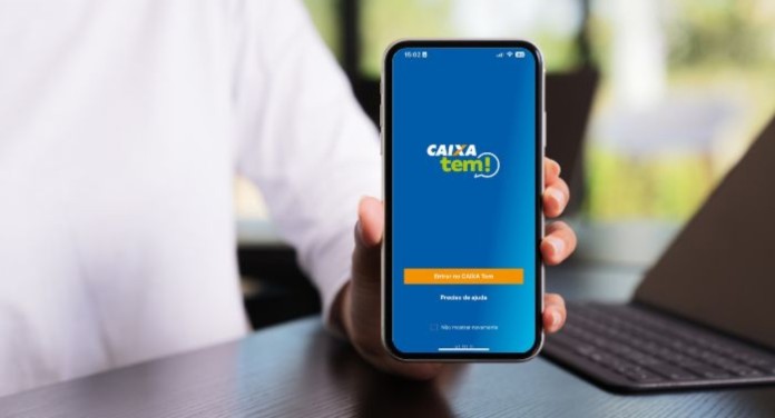 foto mostra pessoa segurando celular com aplicativo do caixa tem