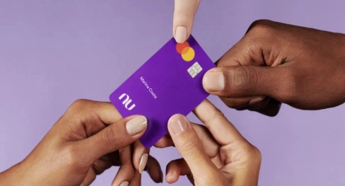 foto mostra pessoas segurando cartão de crédito do nubank