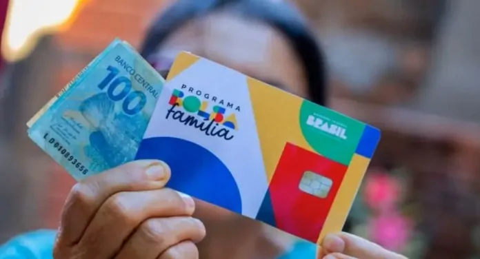 na foto, beneficiário segurando o dinheiro do valor pago pelo Bolsa Família