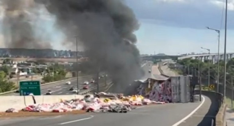 Carreta tomba e pega fogo na BR-448 durante acidente: trânsito bloqueado e fumaça intensa na divisa de Canoas e Porto Alegre